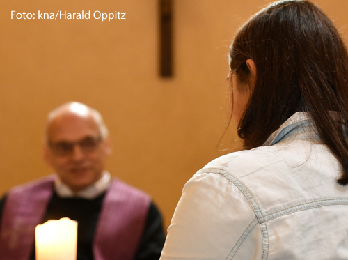 Eine Frau spricht mit einem Priester.