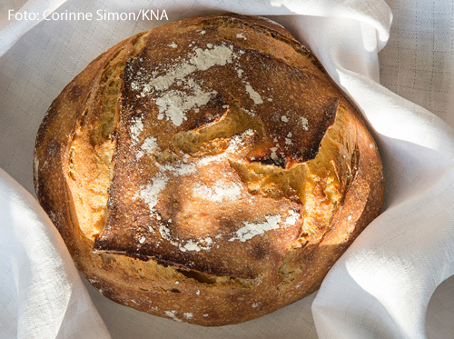 Ein Laib Brot liegt auf einer weißen Tischdecke