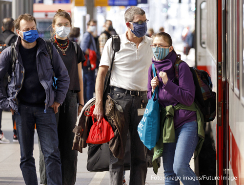 Menschen tragen am Bahnhof Masken 