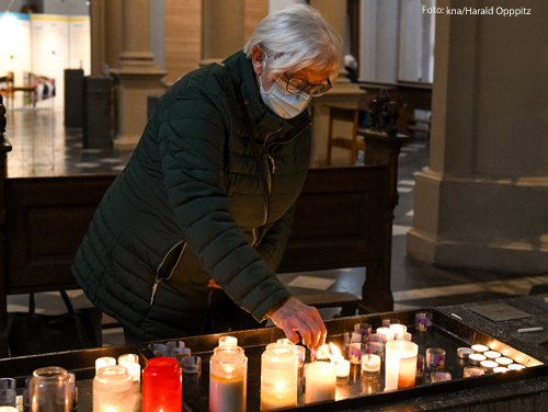 Eine Frau zündet eine Kerze in einer Kirche an. 