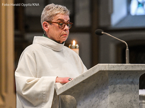 	Eine Frau trägt liturgische Kleidung und steht am Ambo in einer Kirche in Bonn