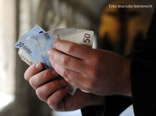 Ein Mann hält Geldscheine in der Hand. 