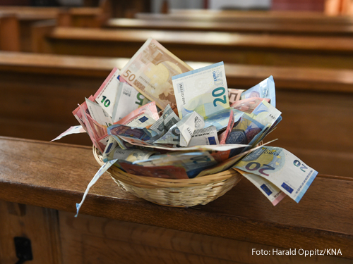 Ein Korb mit Geld steht in einer Kirchenbank. 