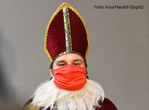 Ein Mann trägt ein Nikolaus-Kostüm und einen Mundschutz. 