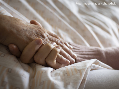 Eine Frau hält die Hand einer Patientin in einem Pflegeheim. 