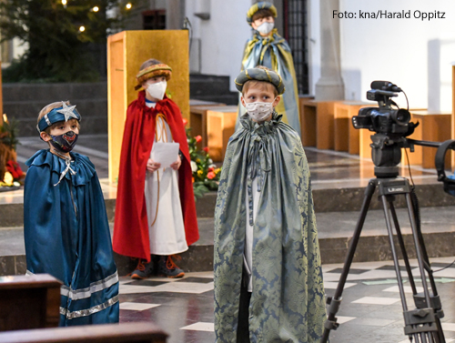 Kinder, die als Sternsinger gekleidet sind drehen in einer Bonner Kirche ein Video. Neben ihnen steht eine Kamera auf einem Stativ. 