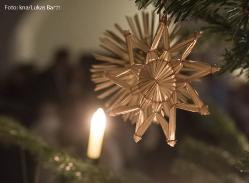 Eine Kerze und ein Stern an einem Christbaum