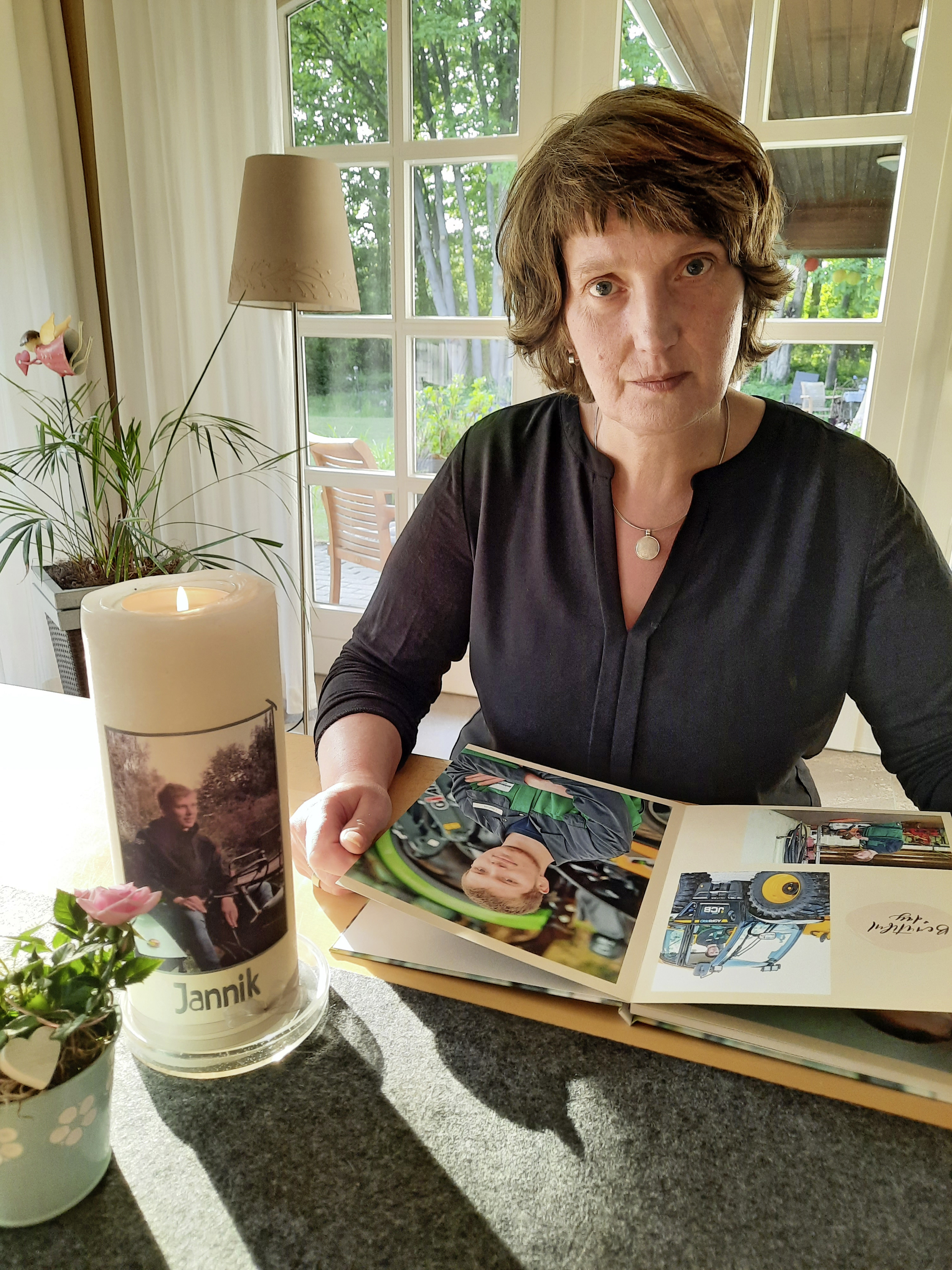 Ene Frau sitzt an einem Tisch. Vor ihr eine Kerze und ein Fotoalbum