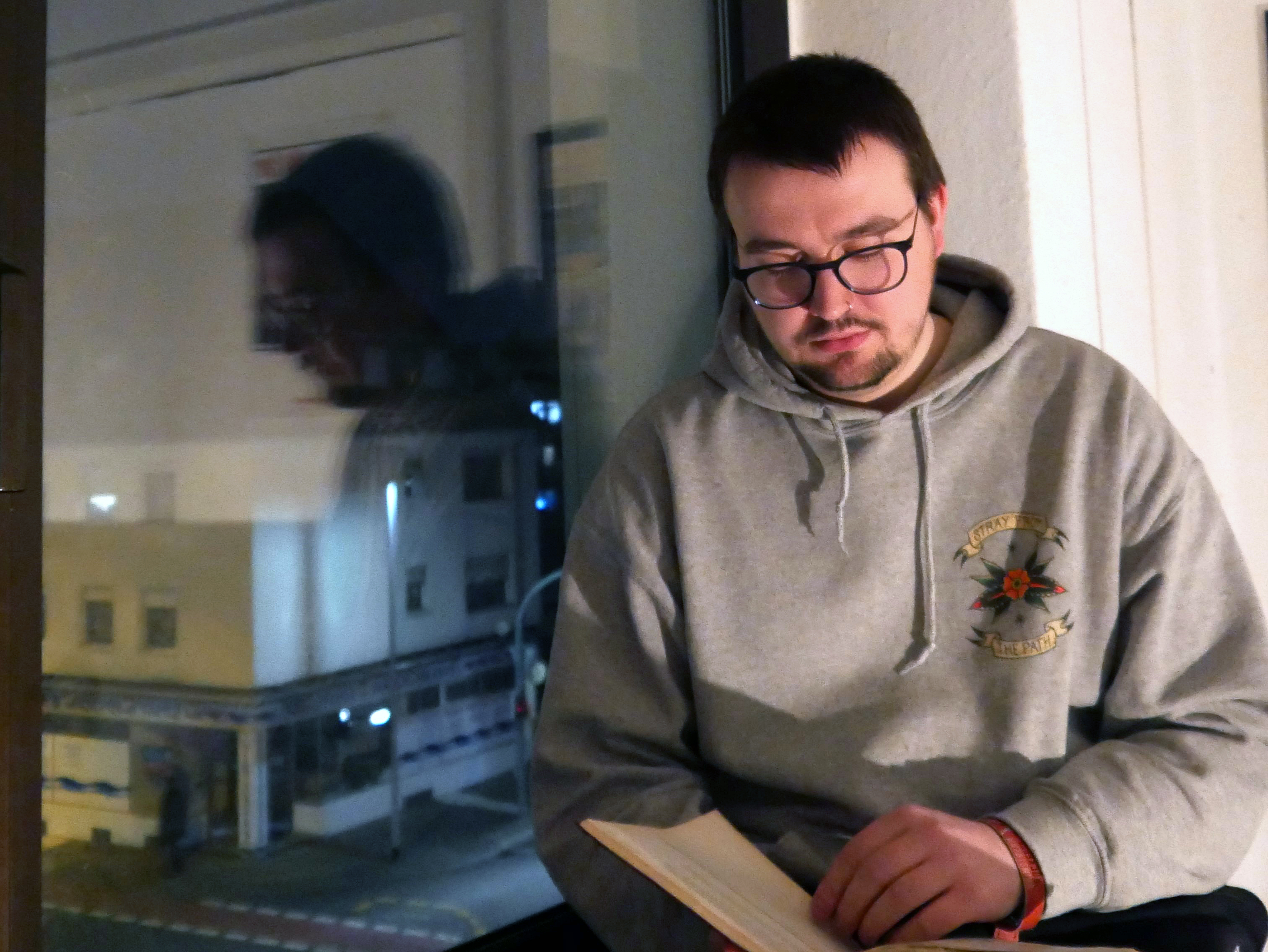 Fabian Kühneman am Fenster mit einem Buch in der Hand