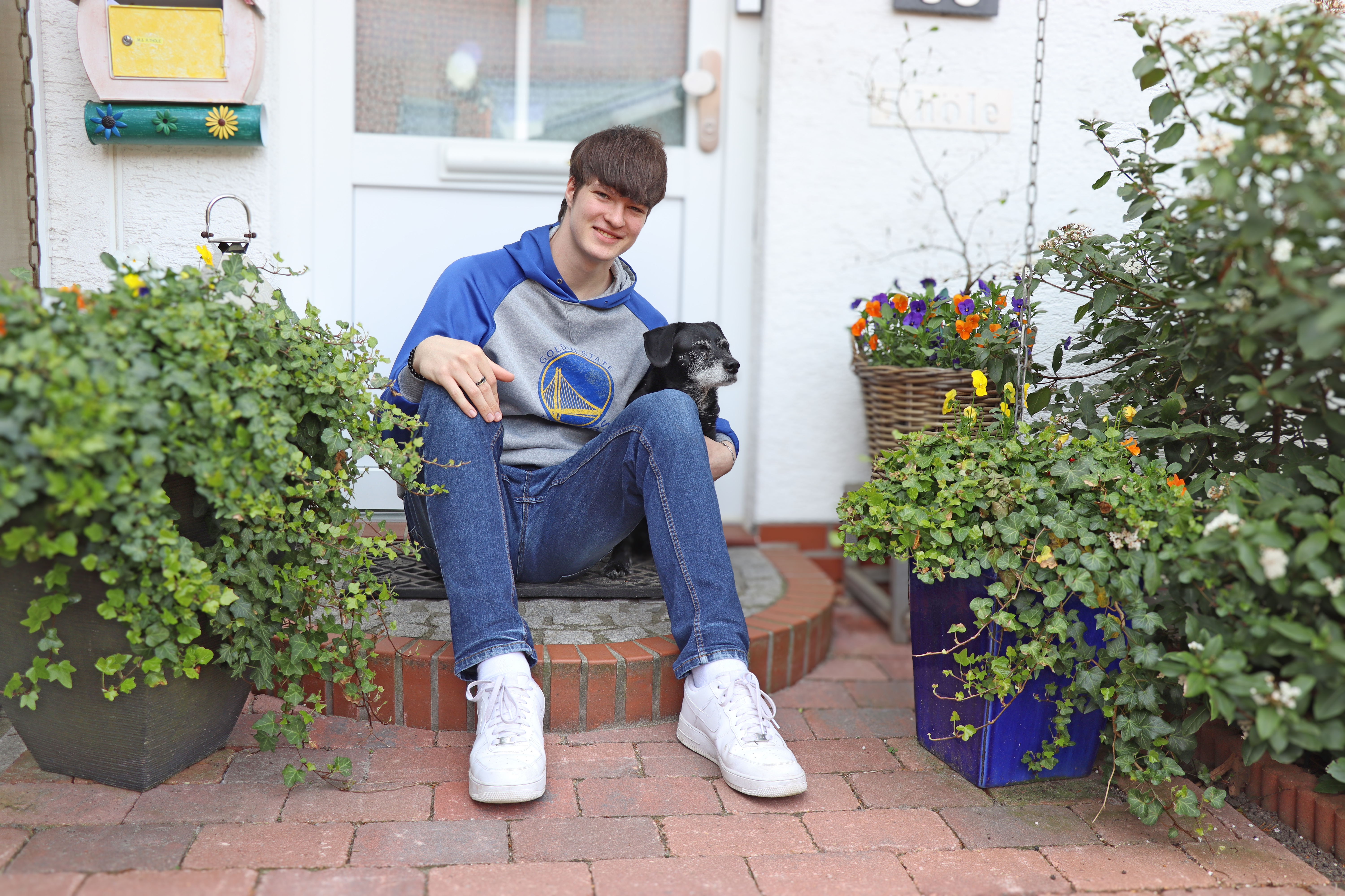 ein junger Mann mit Hund vor einem haus