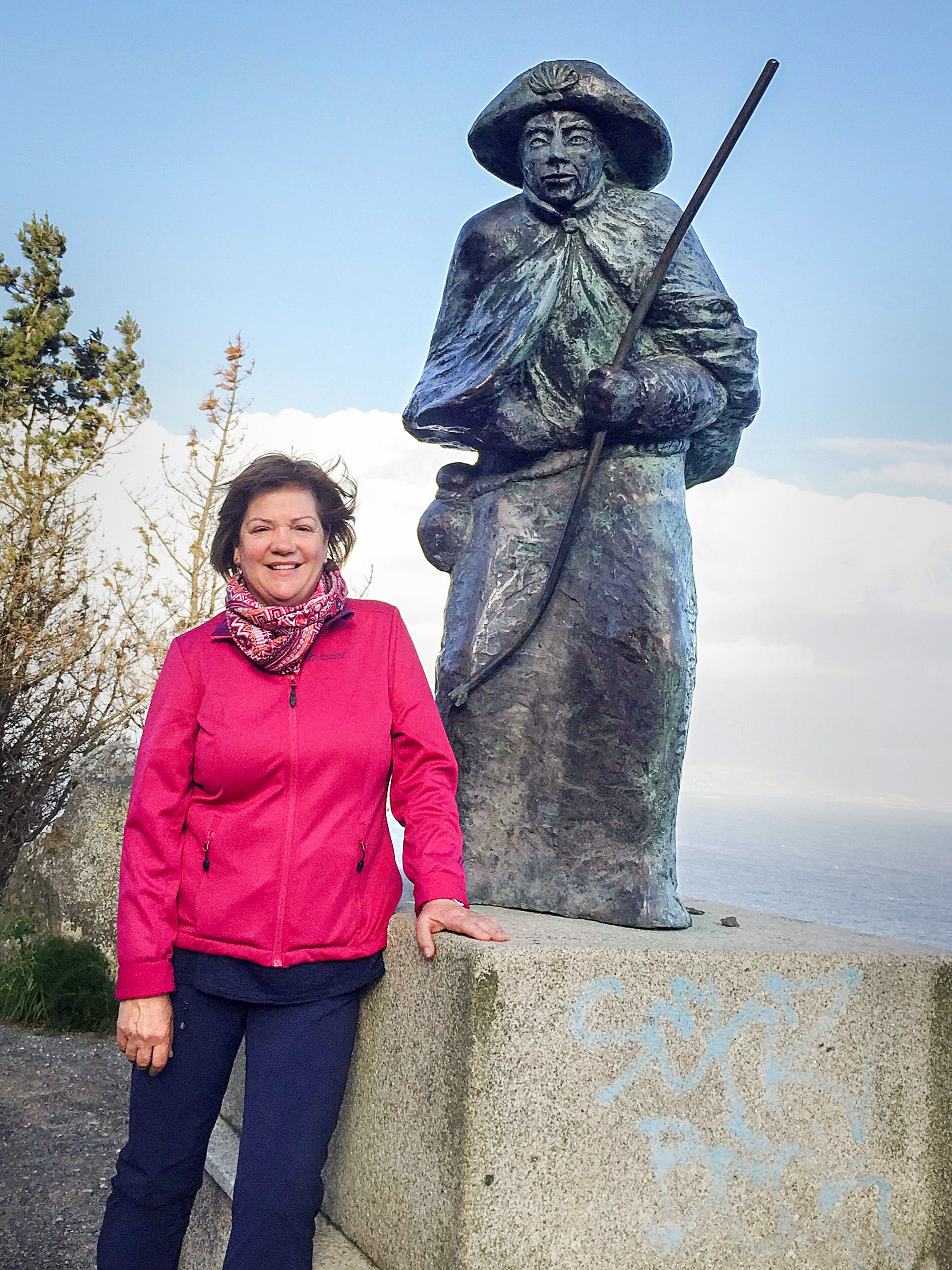 Frau lehnt neben Statue auf einem Berg