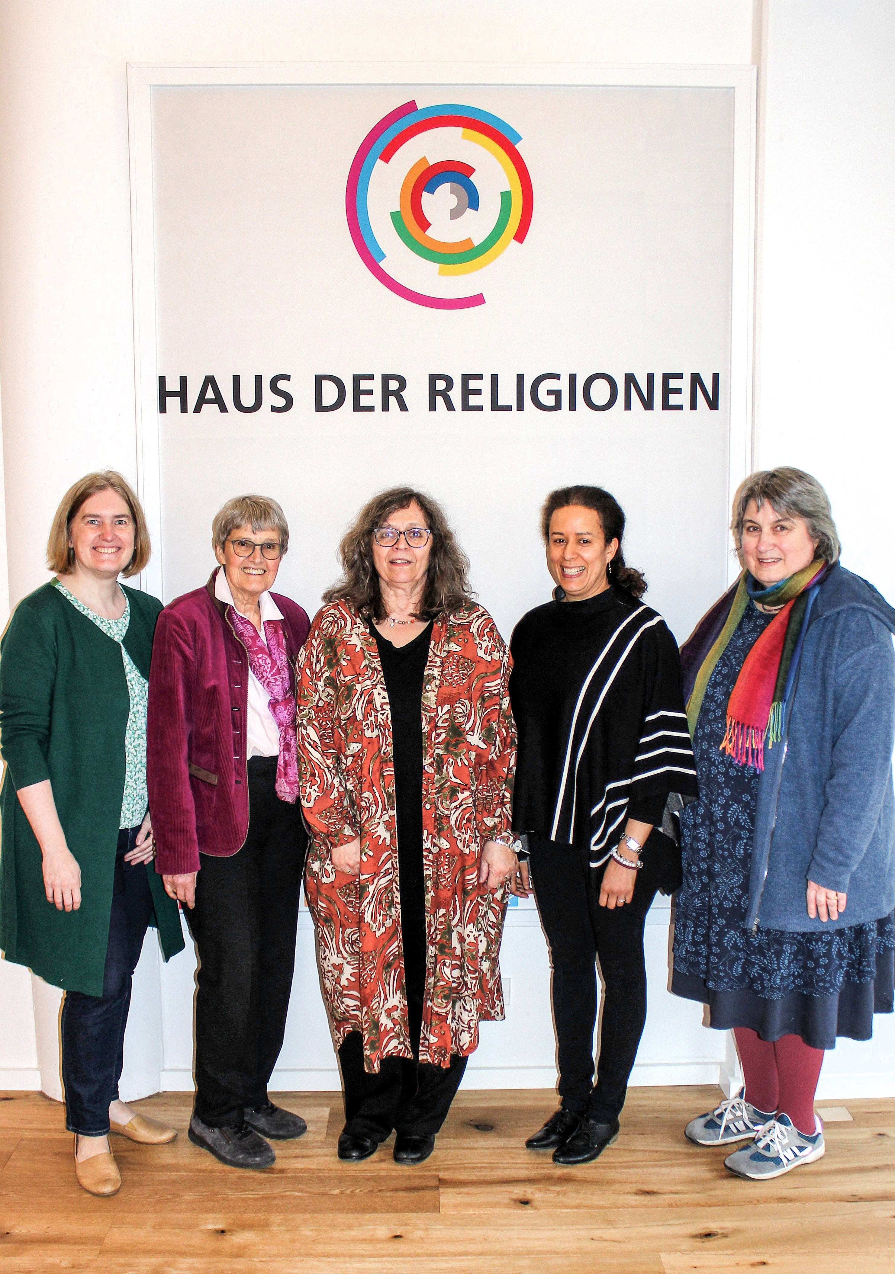 fünf Frauen stehen vor dem Logo der Haus der Religionen