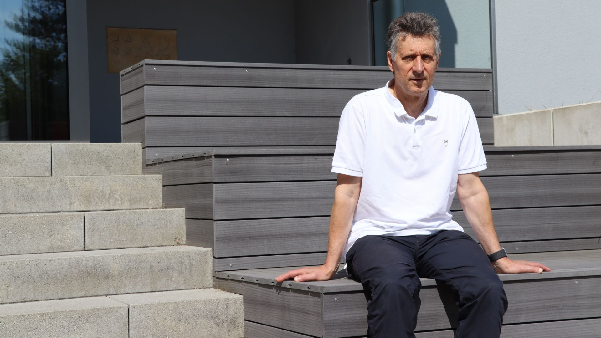Ein Mann sitzt auf einer Treppe und schaut in die Kamera