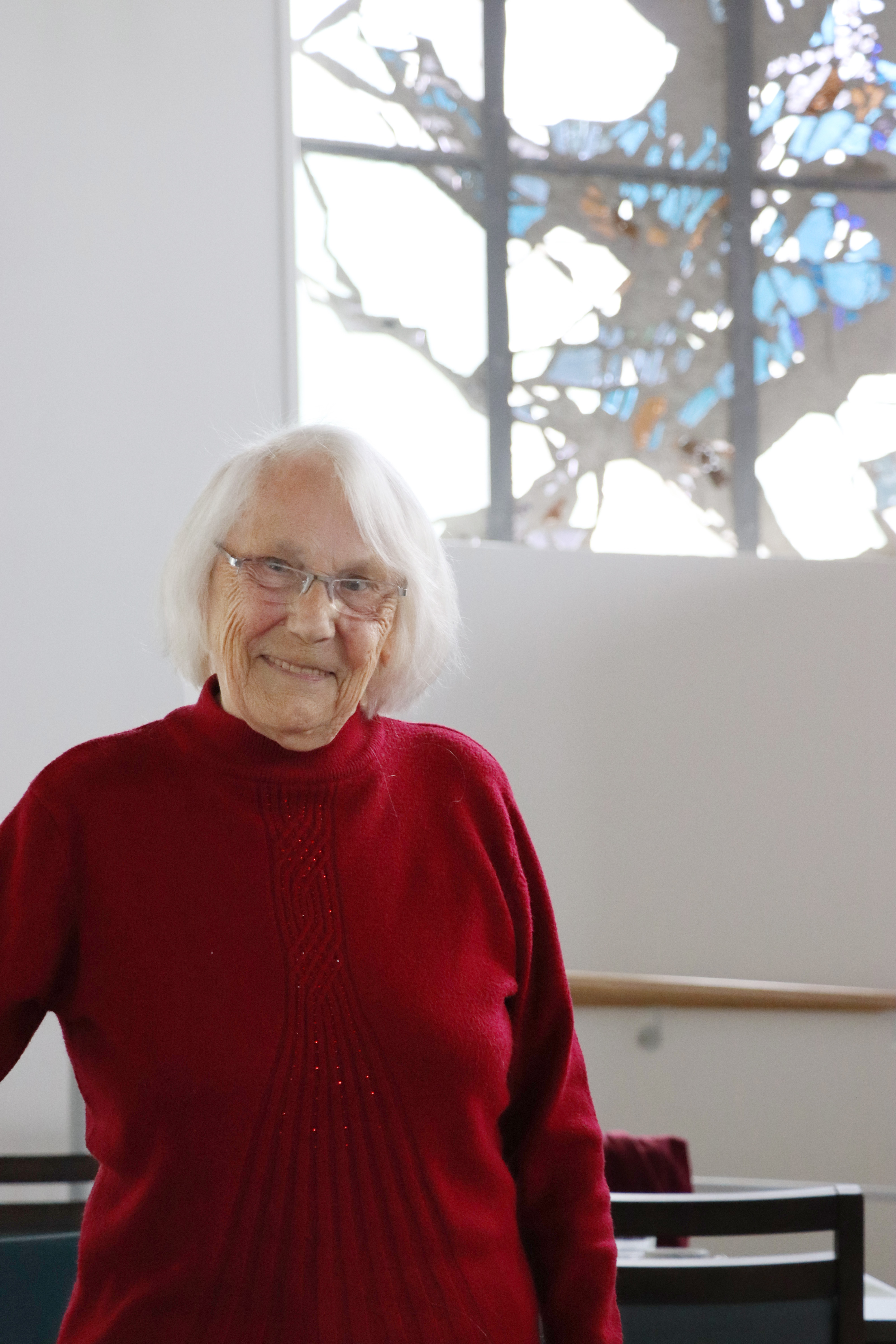 Eine Frau im roten Pullover steht vor einem Fenster