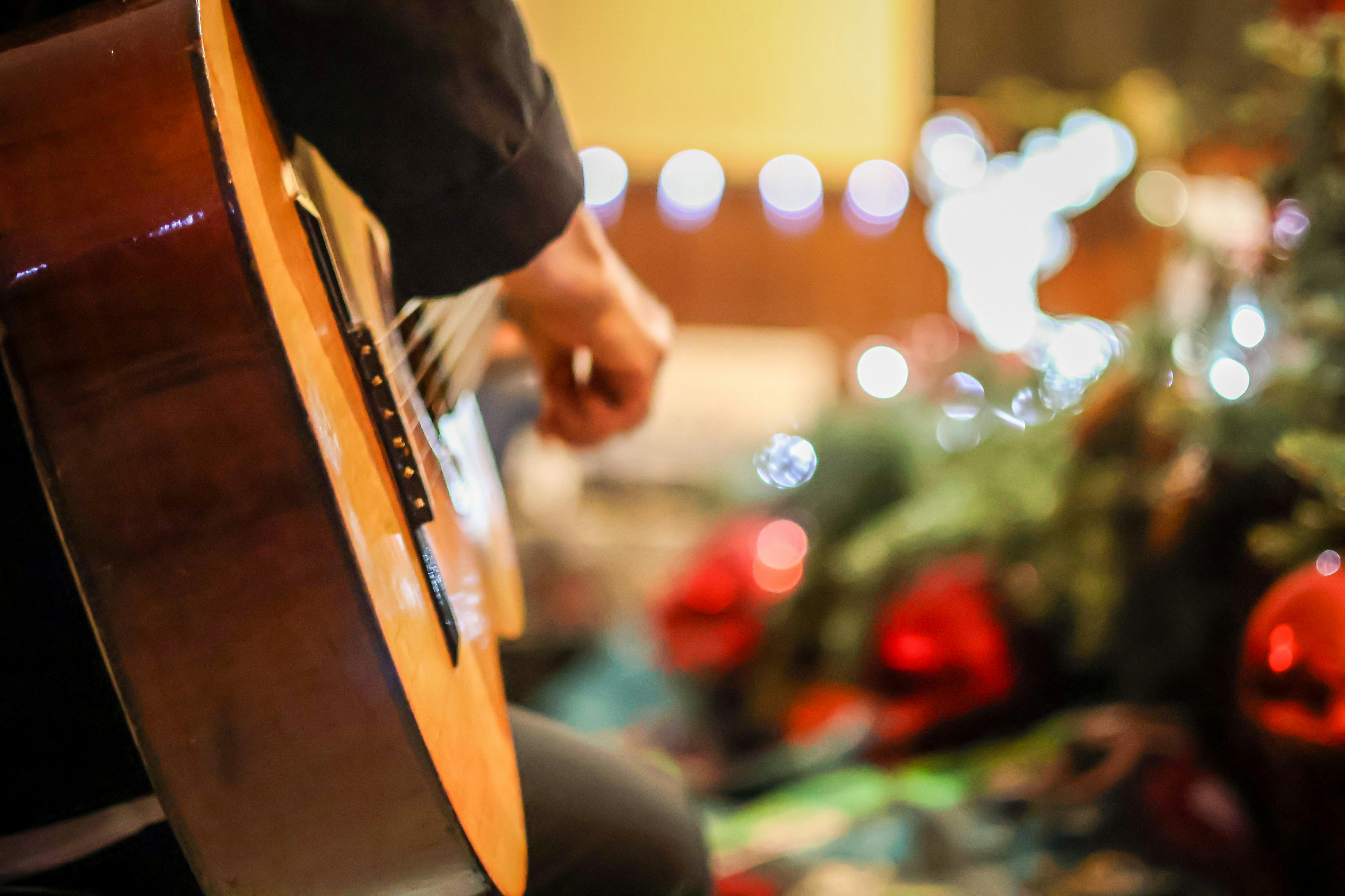 Nahaufnahme Gitarre. Im Hintergrund sind Lichter und Teile eines Weihnachtsbaumes zu sehen.