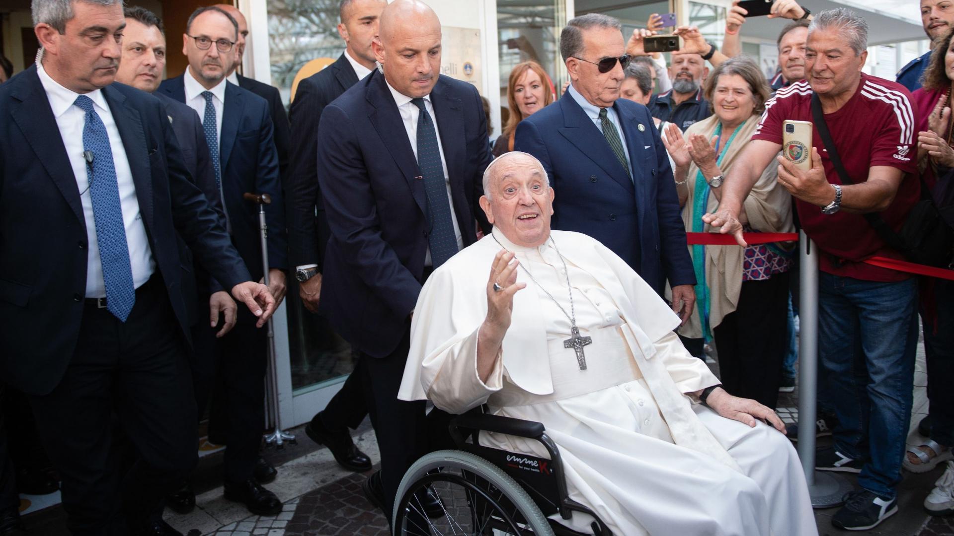 Papst Franziskus verlässt im Rollstuhl sitzend und von Bodyguards begleitet die Gemelli-Klinik in Rom