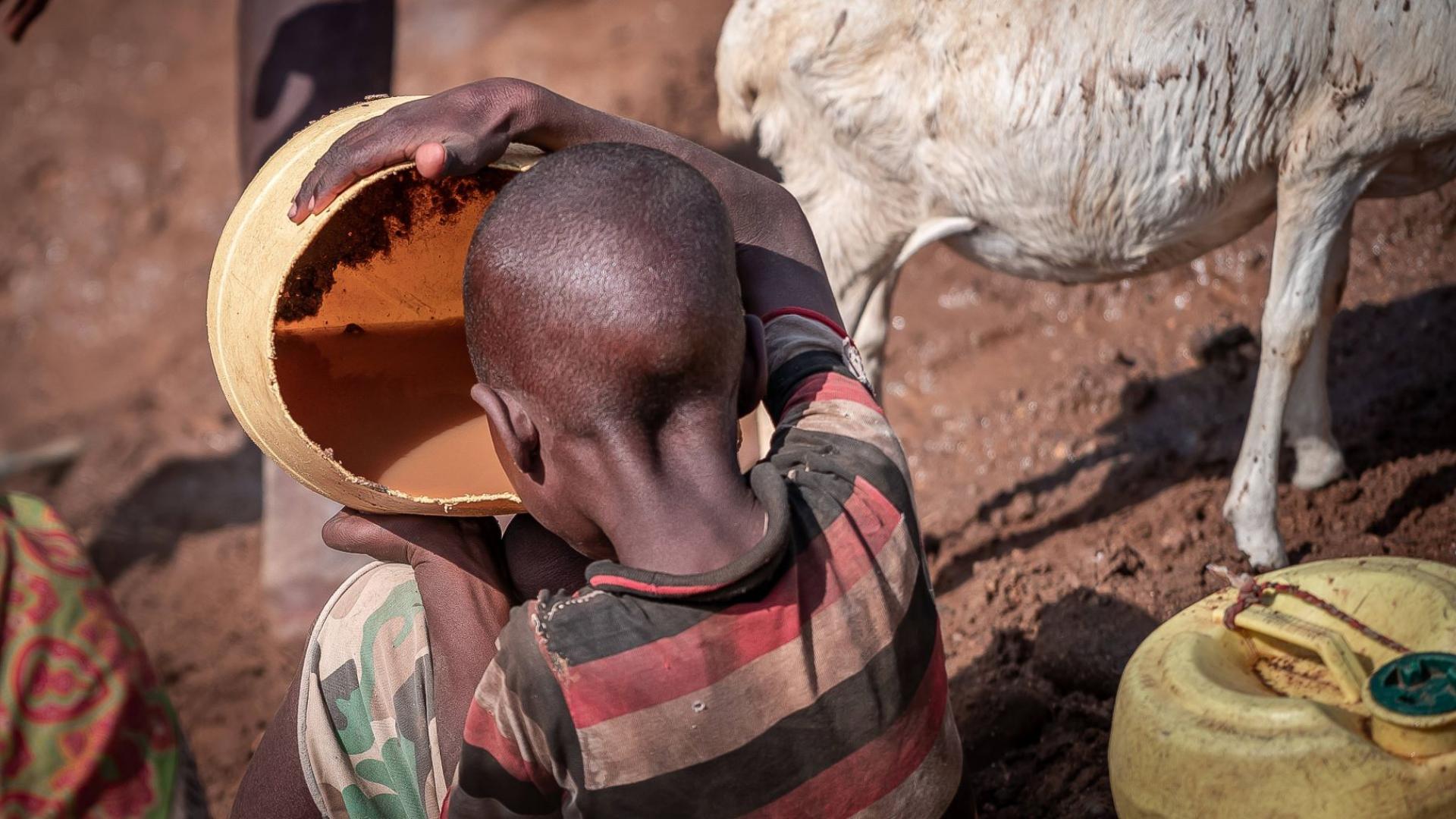 Ein Kind in Kenia trinkt verschmutztes Wasser aus einem Eimer, um in der Dürre zu überleben