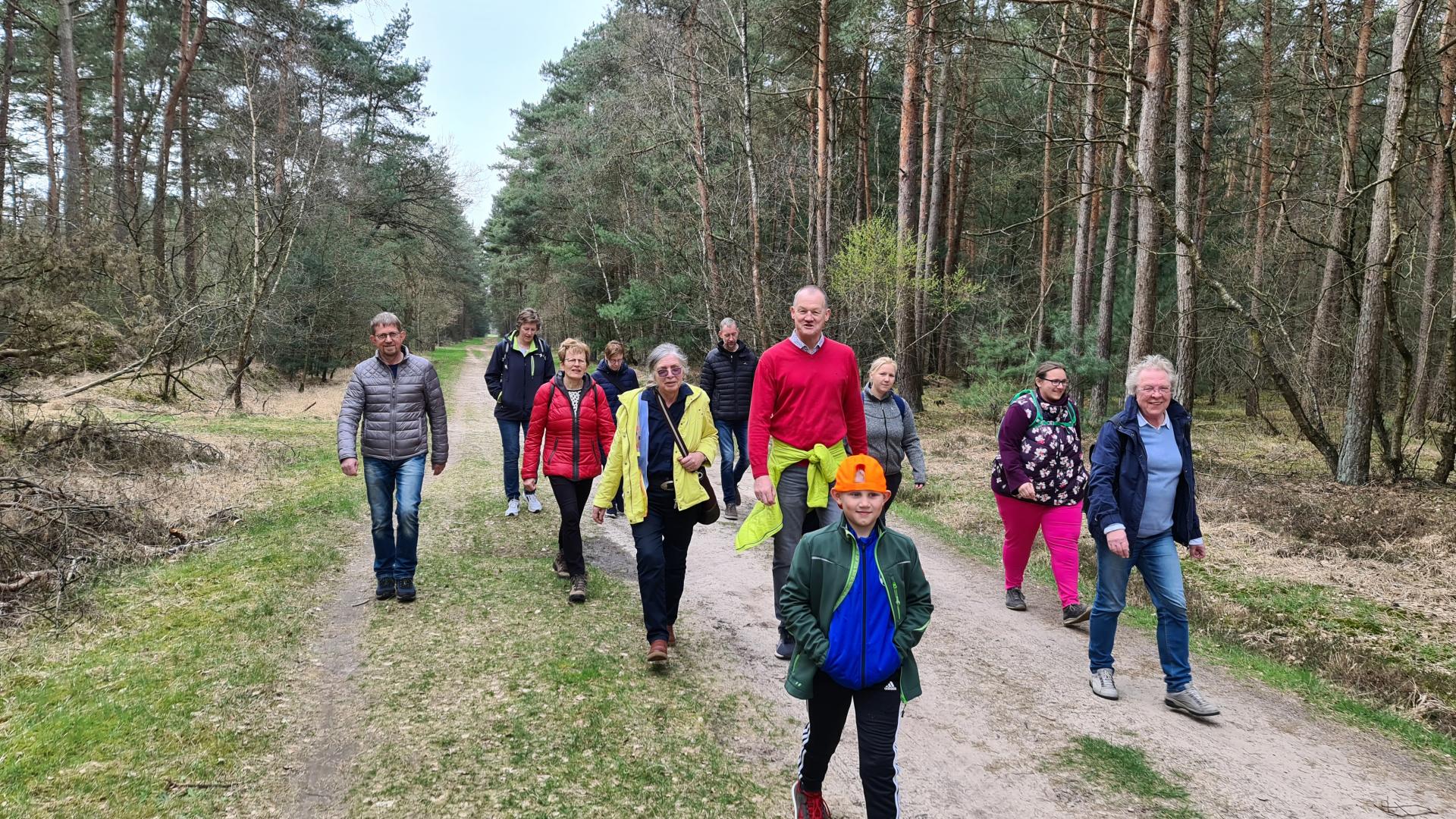 Eine Gruppe von Menschen geht durch einen Wald.