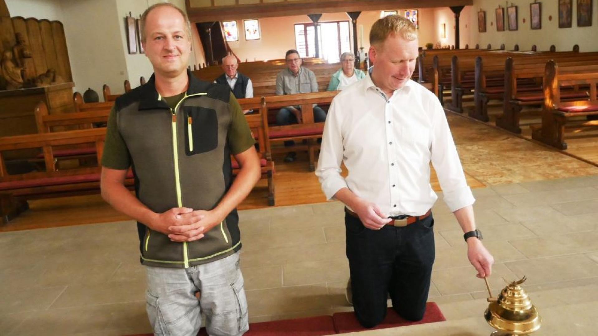 Zwei erwachsene Messdiener knien am Altar