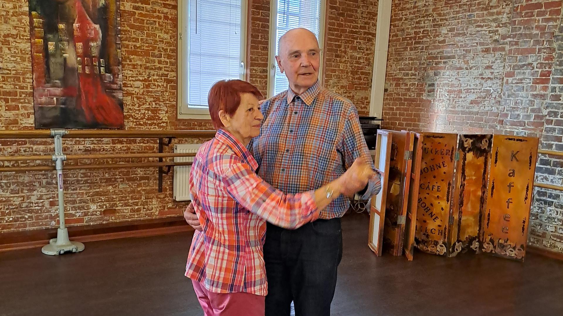 Ein Seniorenpärchen tanzt gemeinsam durch einen Raum