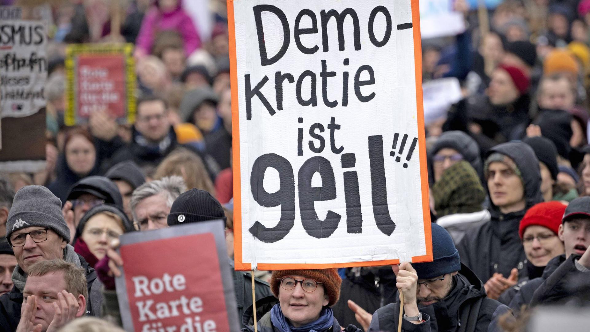 Eine Frau hält ein Schild mit der Aufschrift "Demokratie ist geil"