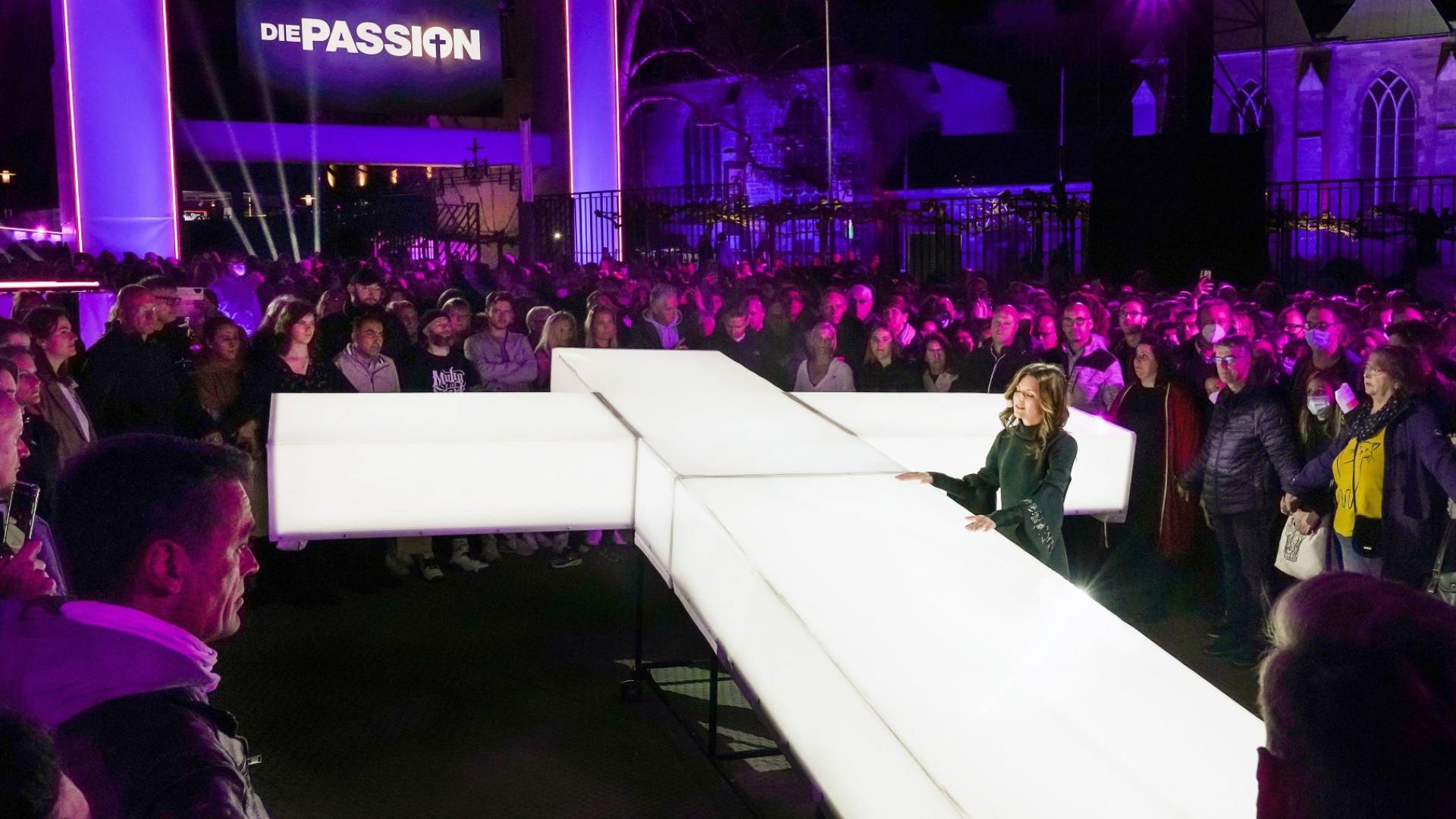 Ein leuchtendes Kreuz ist bei der Passion bei RTL inmitten von Menschen
