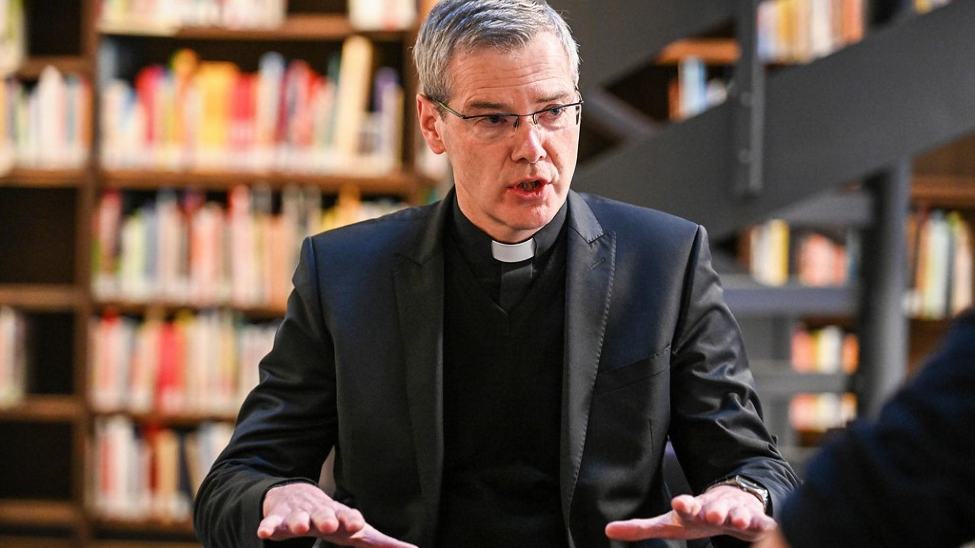 Bischof Heiner Wilmer sitzt im Gespräch in einer Bibliothek