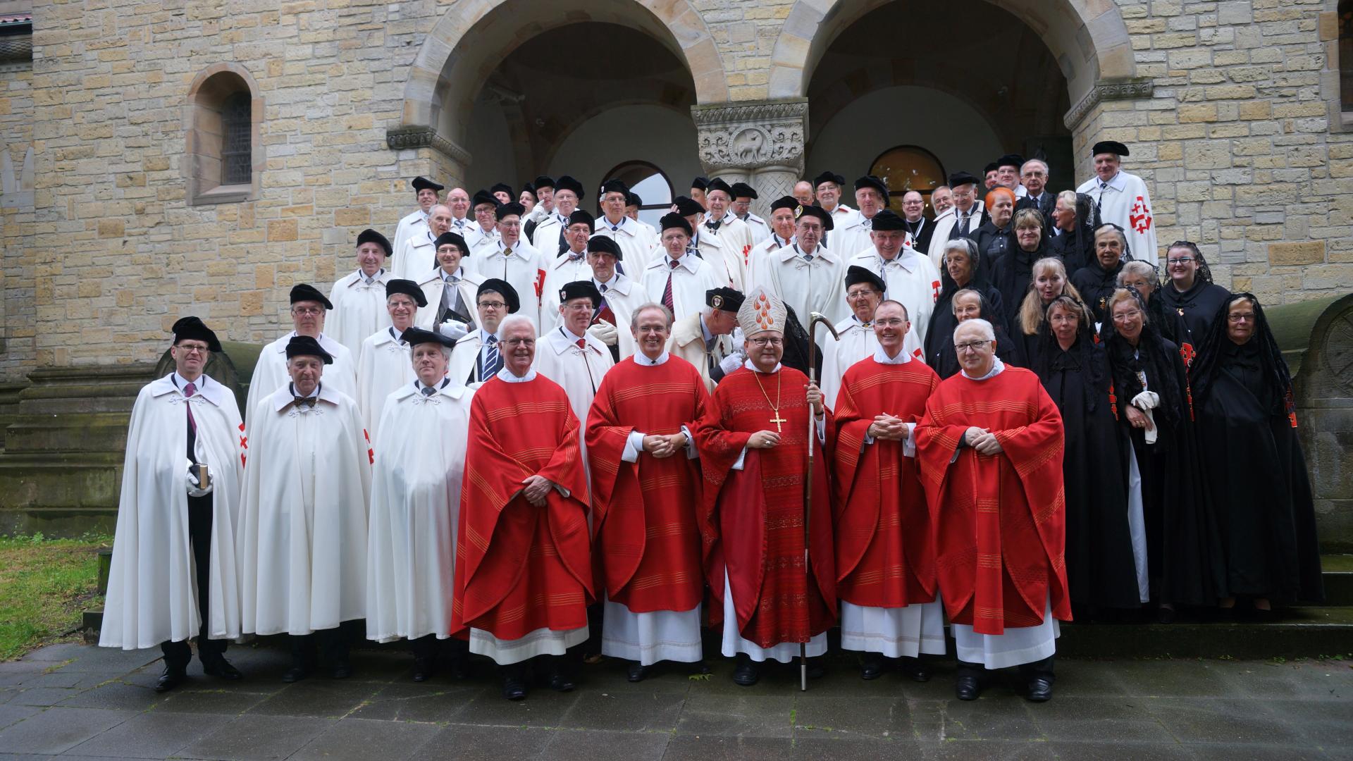 Ein in weiße und rote liturgische Gewänder gekleidete Gruppe von Frauen und Männern