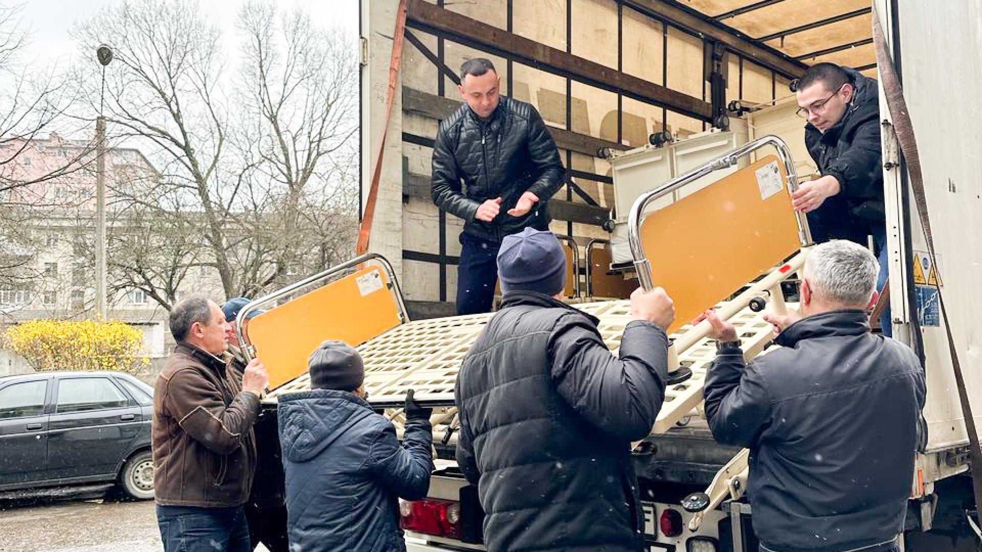 Männer laden ein Bett von einem LKW ab.