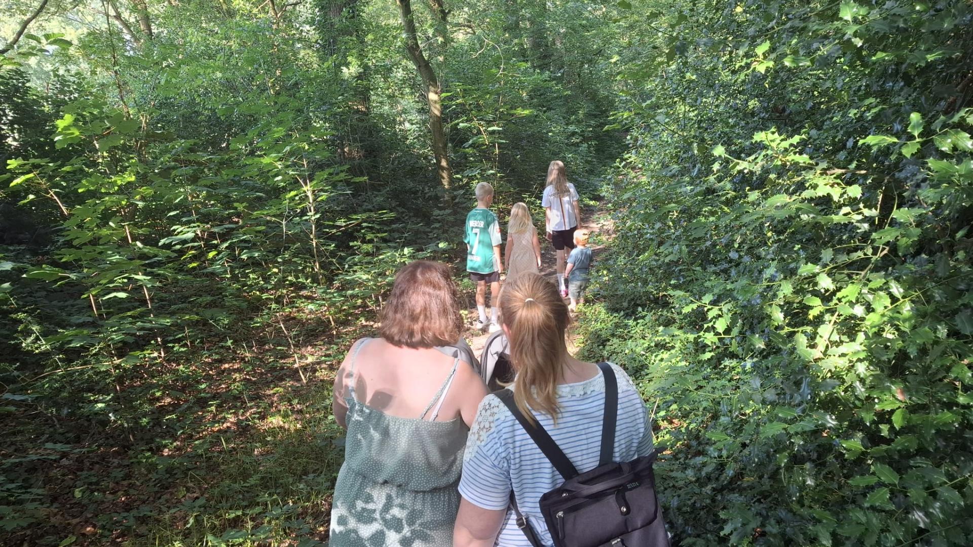 Erwachsene und Kinder spazieren  durch einen Wald.