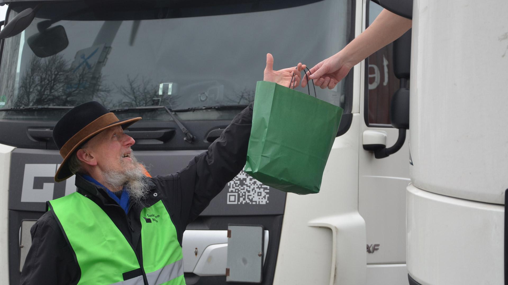 Diakon Franz-Georg Lauck reicht eine Geschenktüte in ein LKW-Führerhaus.