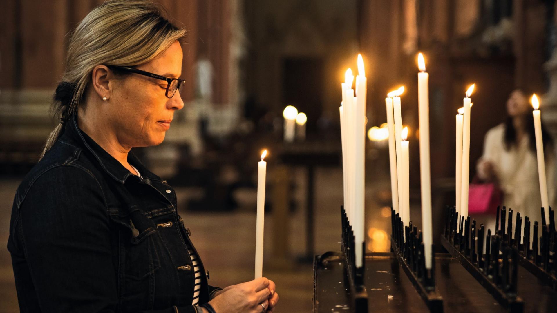 Eine Frau zündet in einer Kirche eine Kerze an