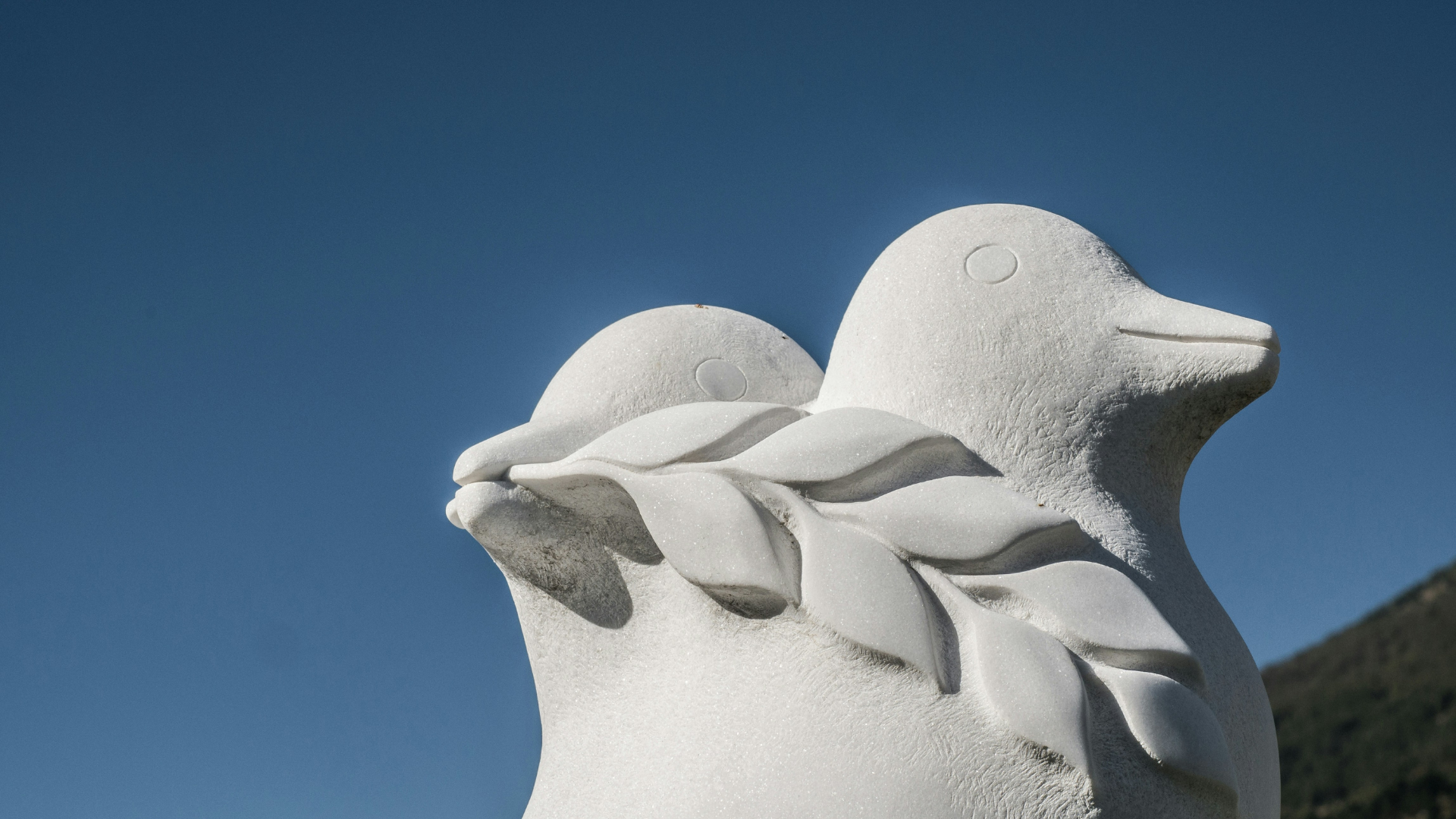 Zwei Friedenstauben aus Stein vor blauem Himmel