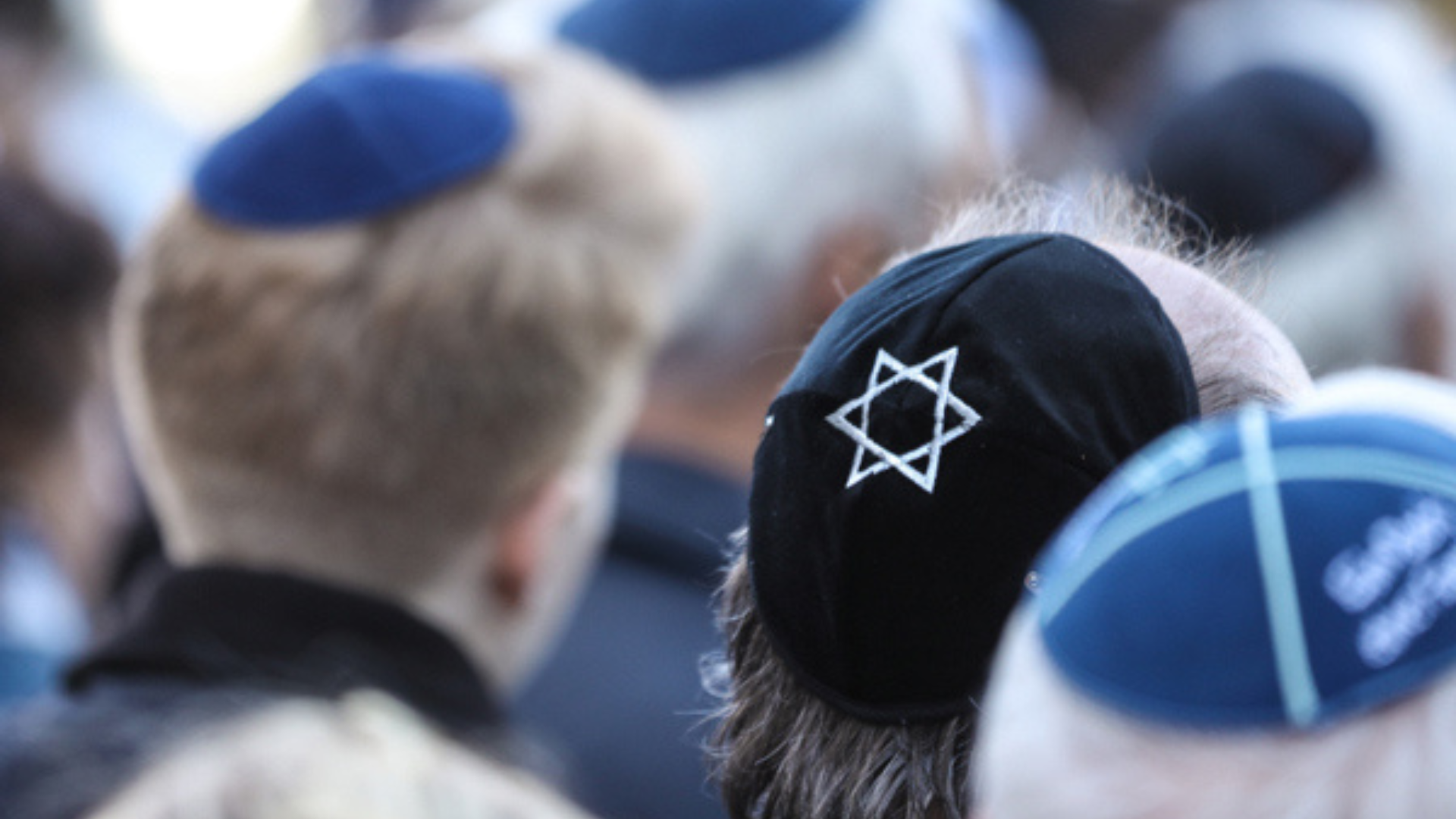 Mehrere Männer aus der Rückansicht tragen eine Kippa mit Davidstern (jüdische Kopfbedeckungen) auf dem Hinterkopf