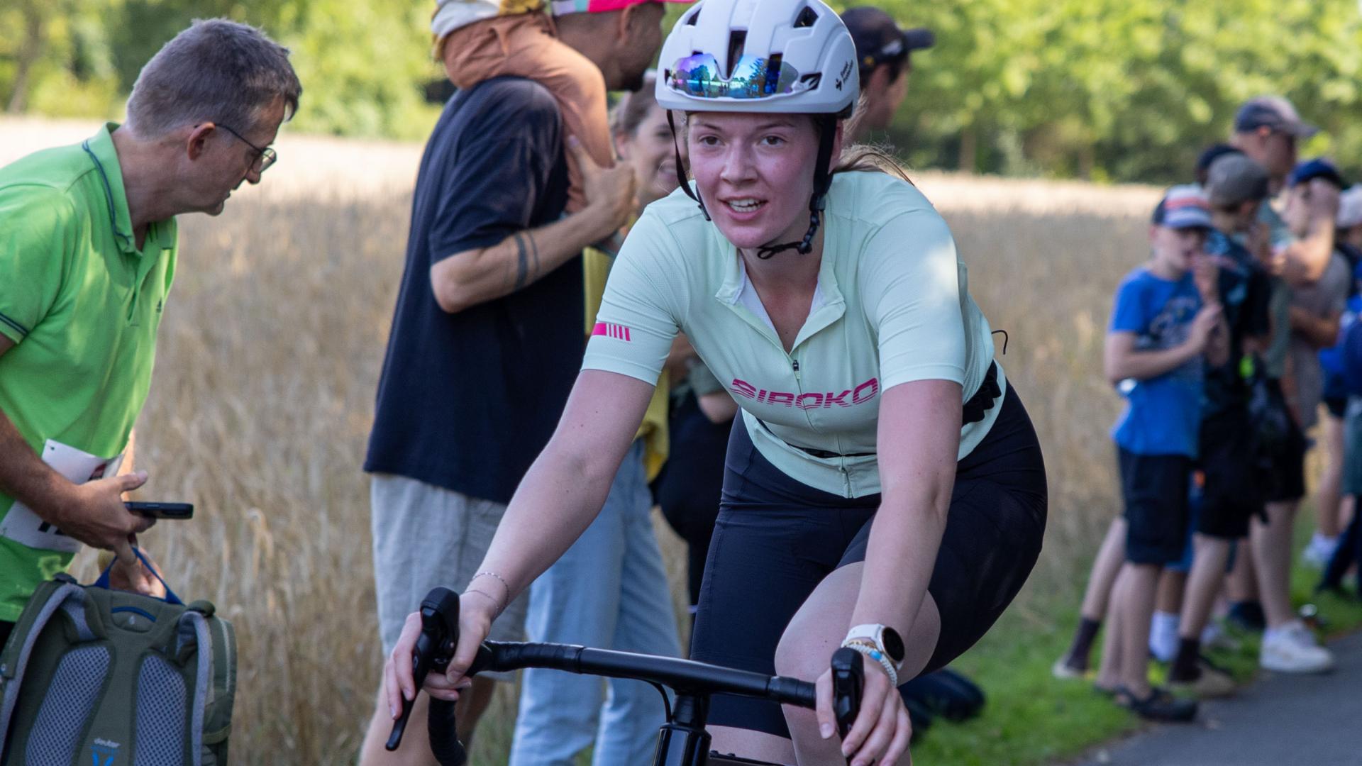 Eine Frau fährt auf einem Rennrad an Zuschauern vorbei. 