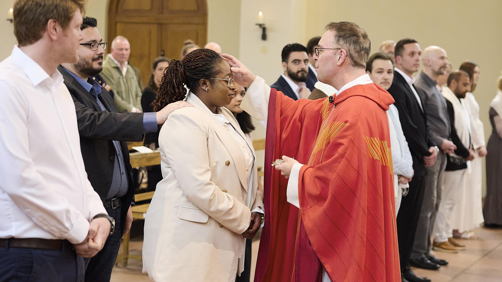 Menschen in der Kirche, eine Frau wird gesalbt.