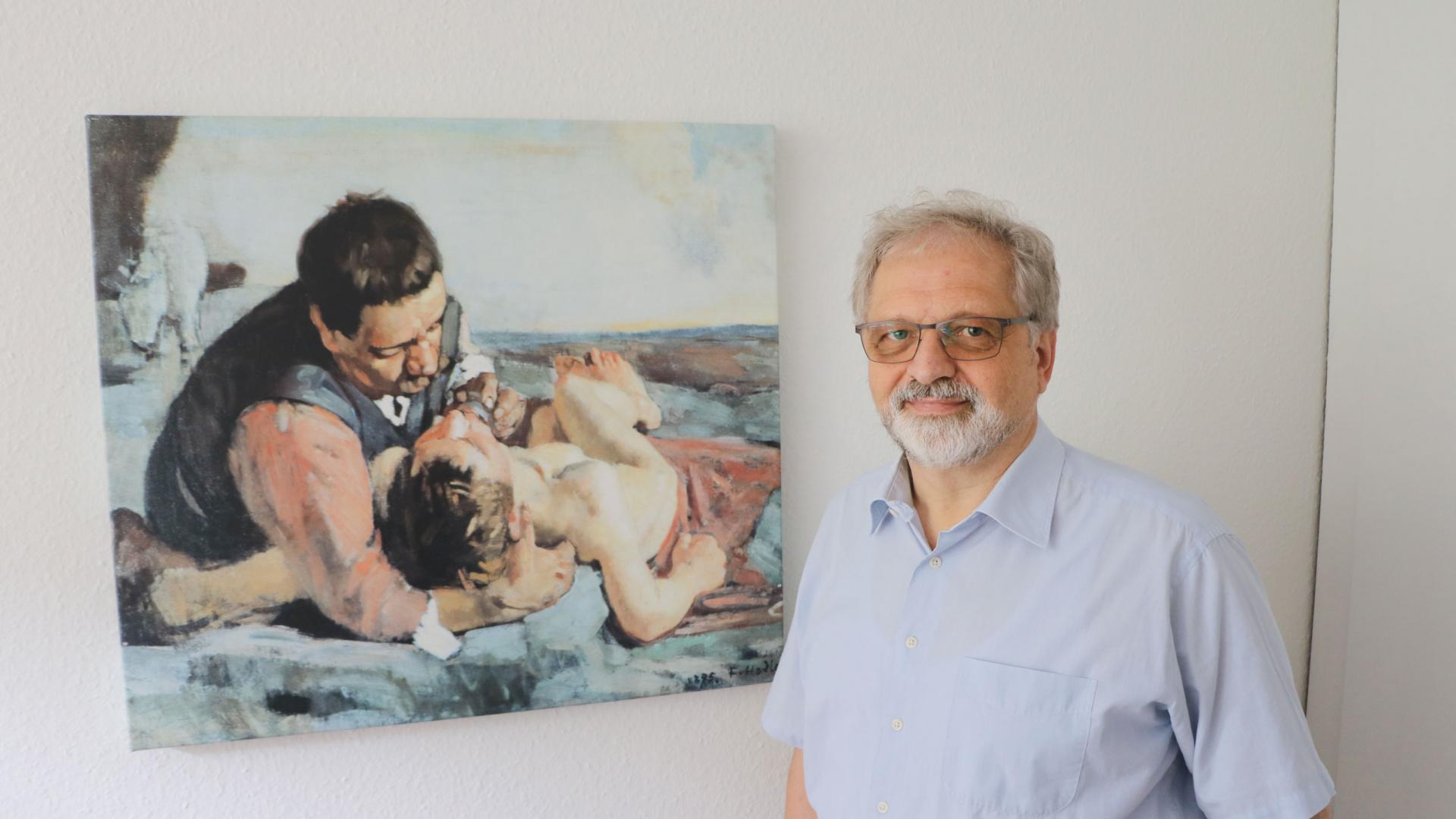 Ein Mann steht vor einem Gemälde.