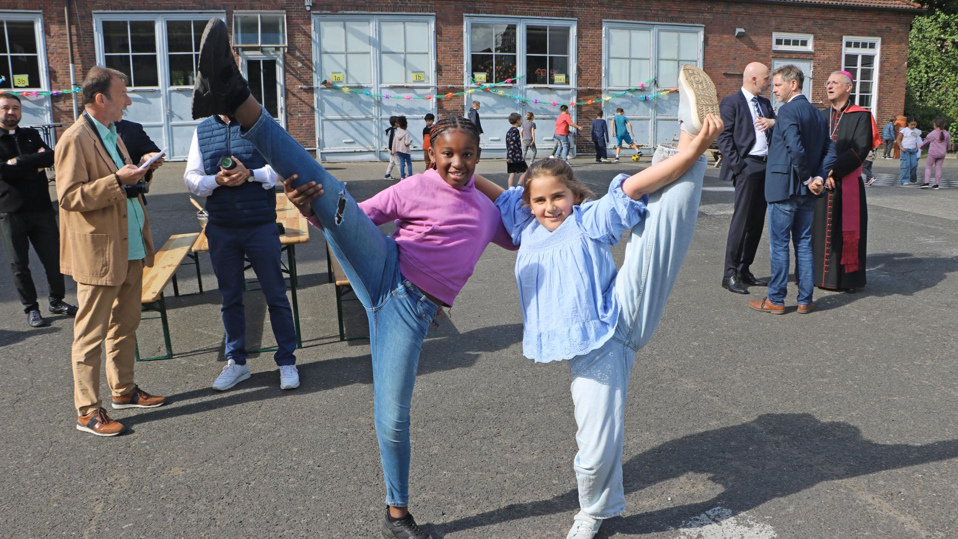 Zwei Mädchen machen artistischer Gymnastik und lächeln in die Kamera.