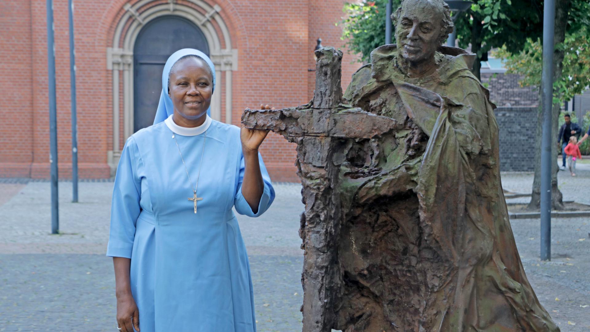 Eine Frau steht neben der Plastik des heiligen Ansgar.