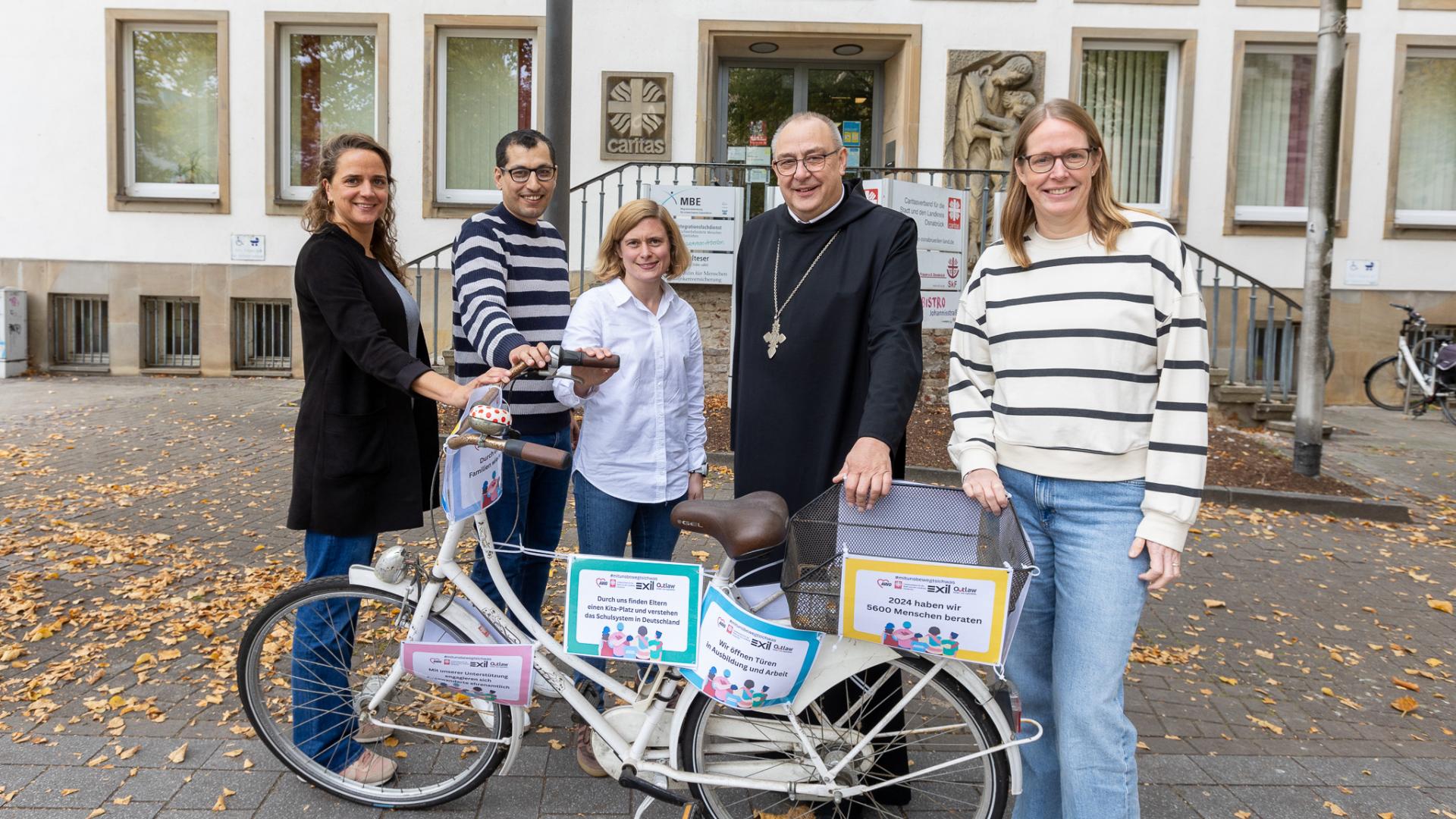 Vier Personen stehen mit dem Osnabrücker Bischof vor einem Fahrrad