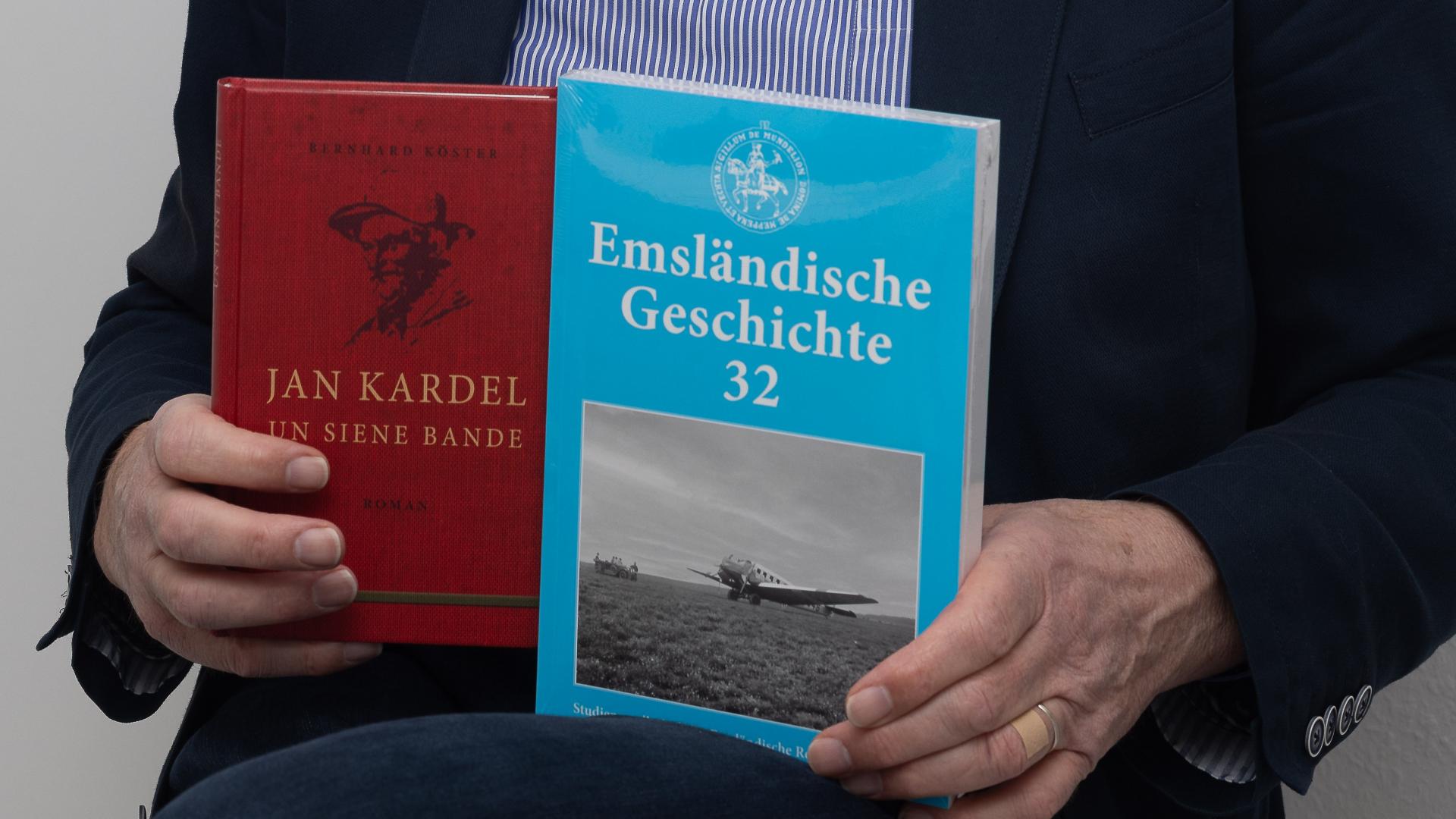 ein Mann hält zwei Bücher