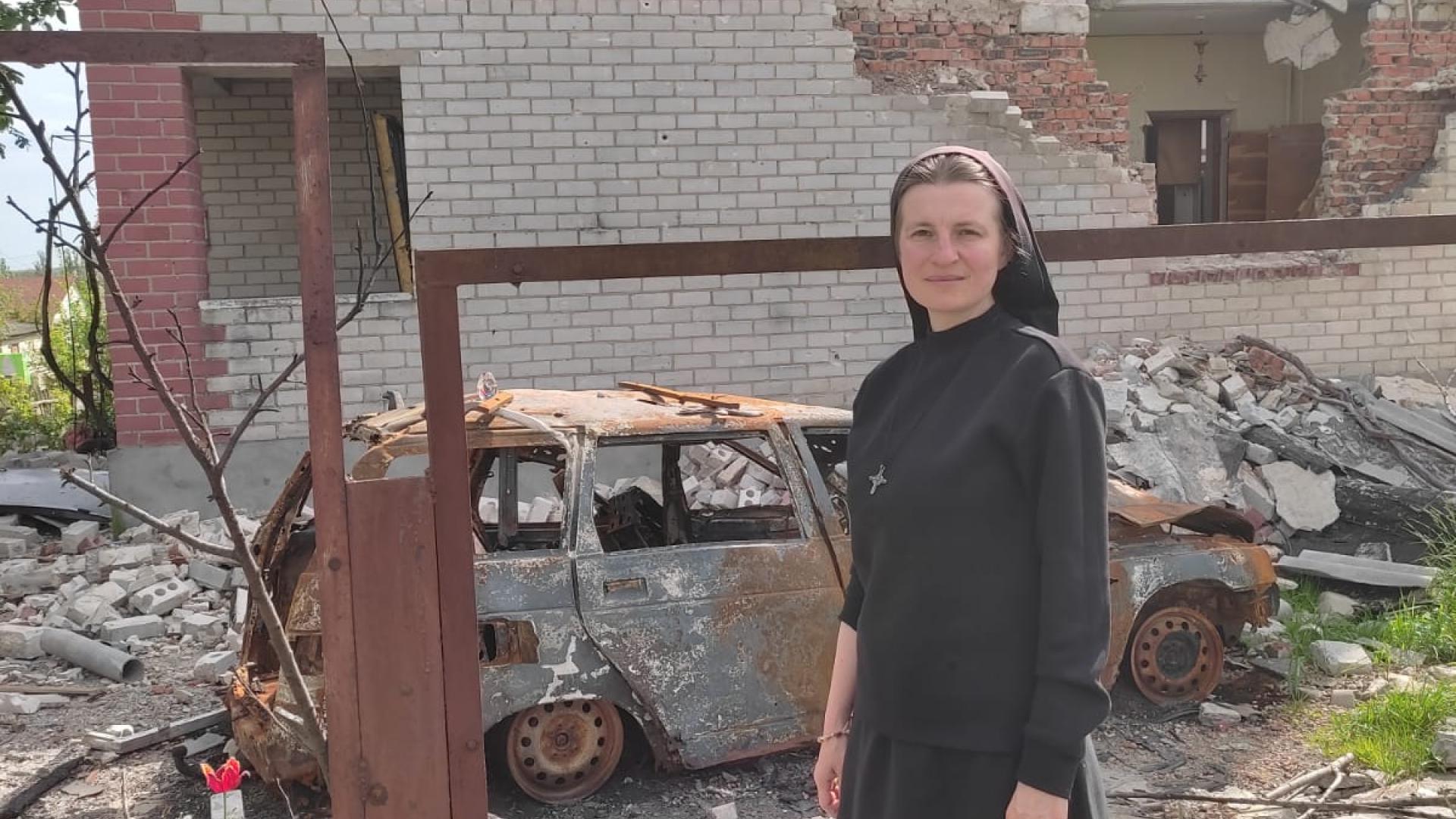 Schwester Teodora Shulak steht in der Ukraine vor einem zerstörten Haus.