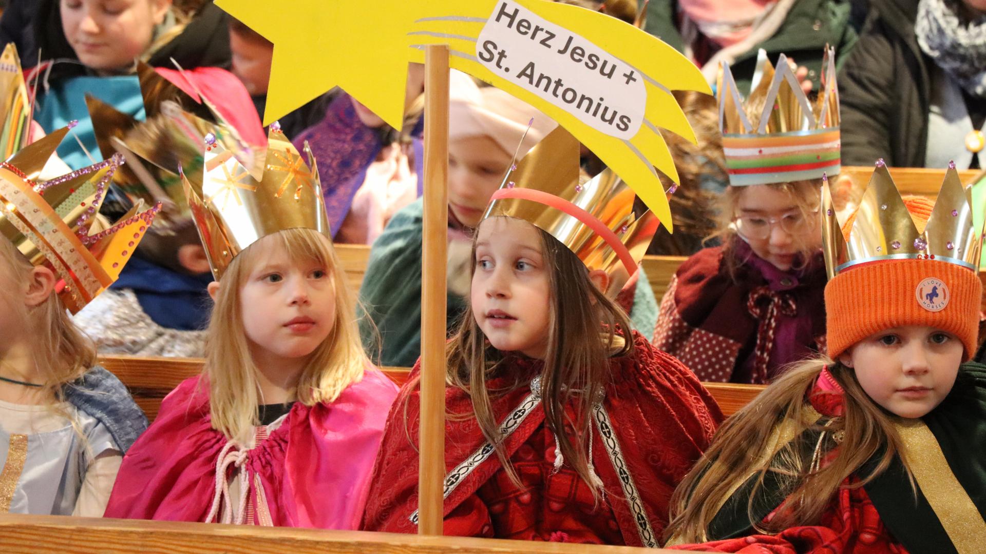 Sternsinger halten einen Holzstern in die Kamera