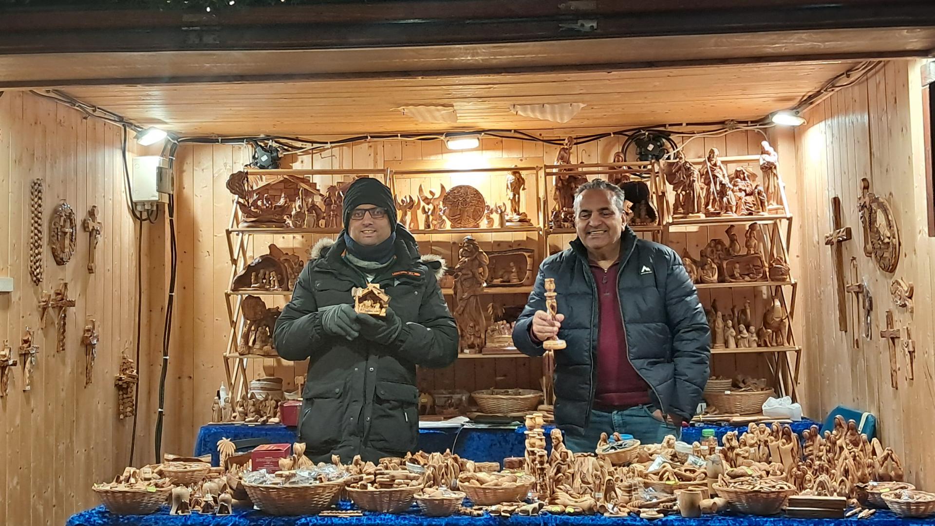 Zwei Männer am Weihnachtsstand mit Krippenfiguren.