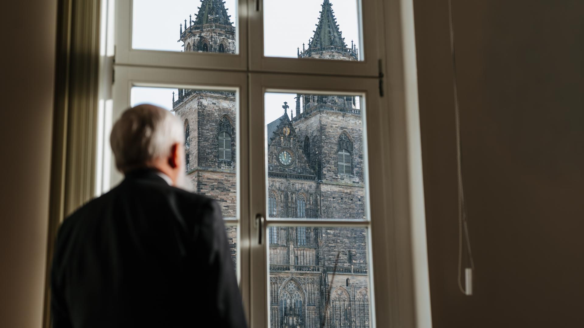 Mann schaut aus dem Fenster auf einen Dom