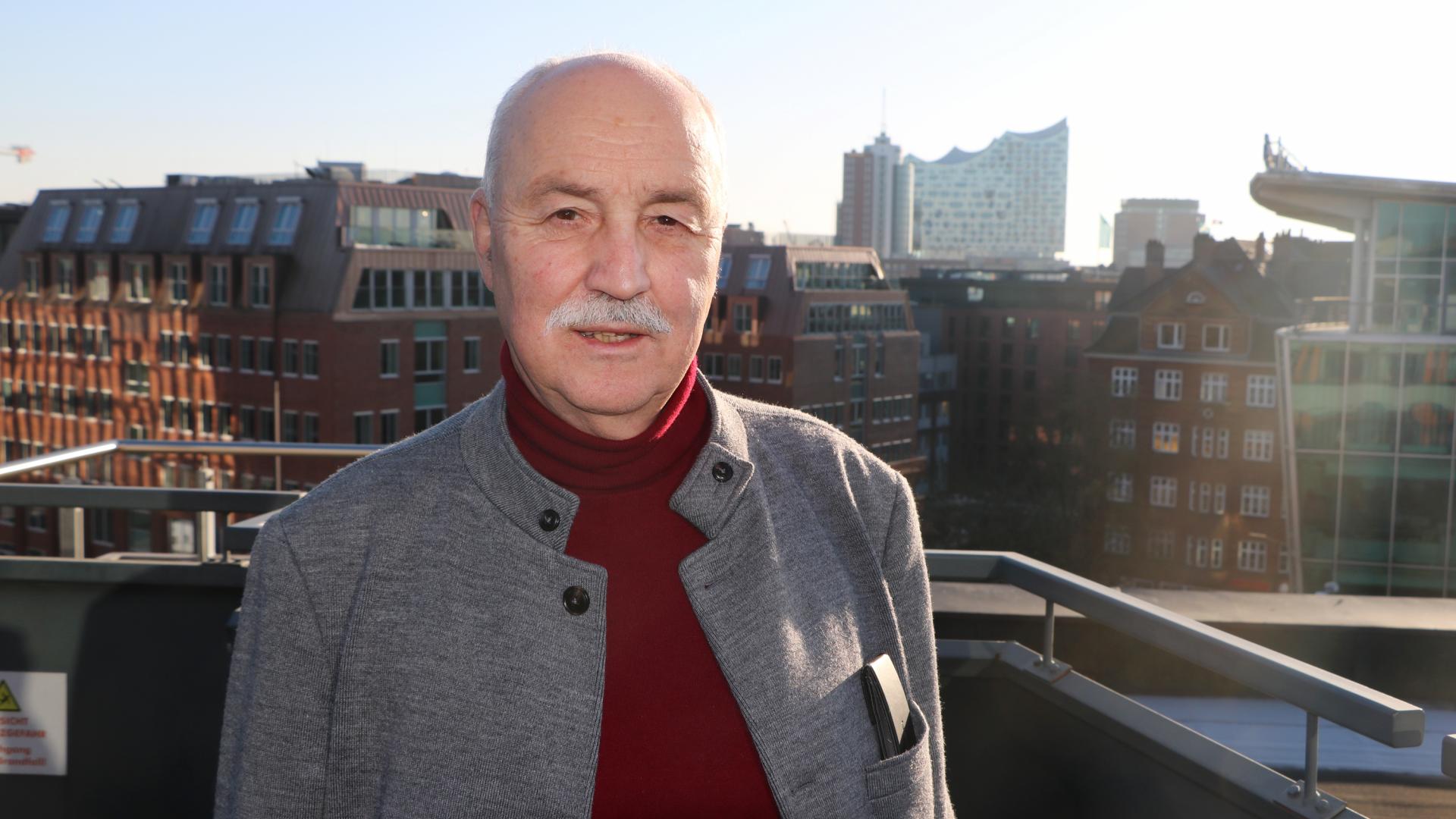 Mann auf einem Balkon, lächelt in die Kamera.