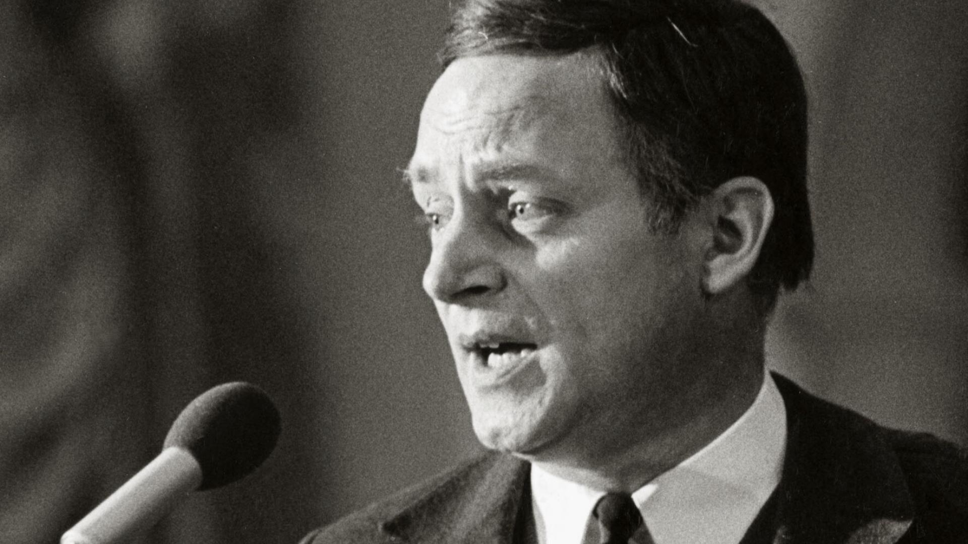 Ein Mann spricht in ein Mikrofon. Schwarz-Weiß Foto