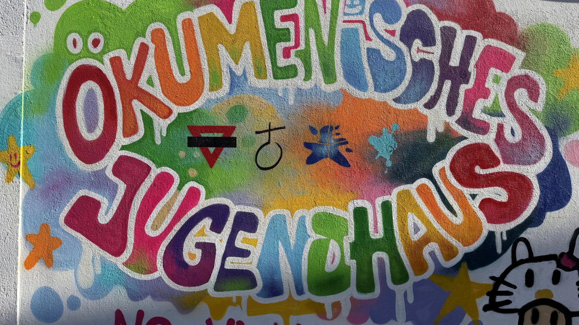 Auf eine Wand ist in bunten Buchstaben Ökumenisches Jugendhaus geschrieben