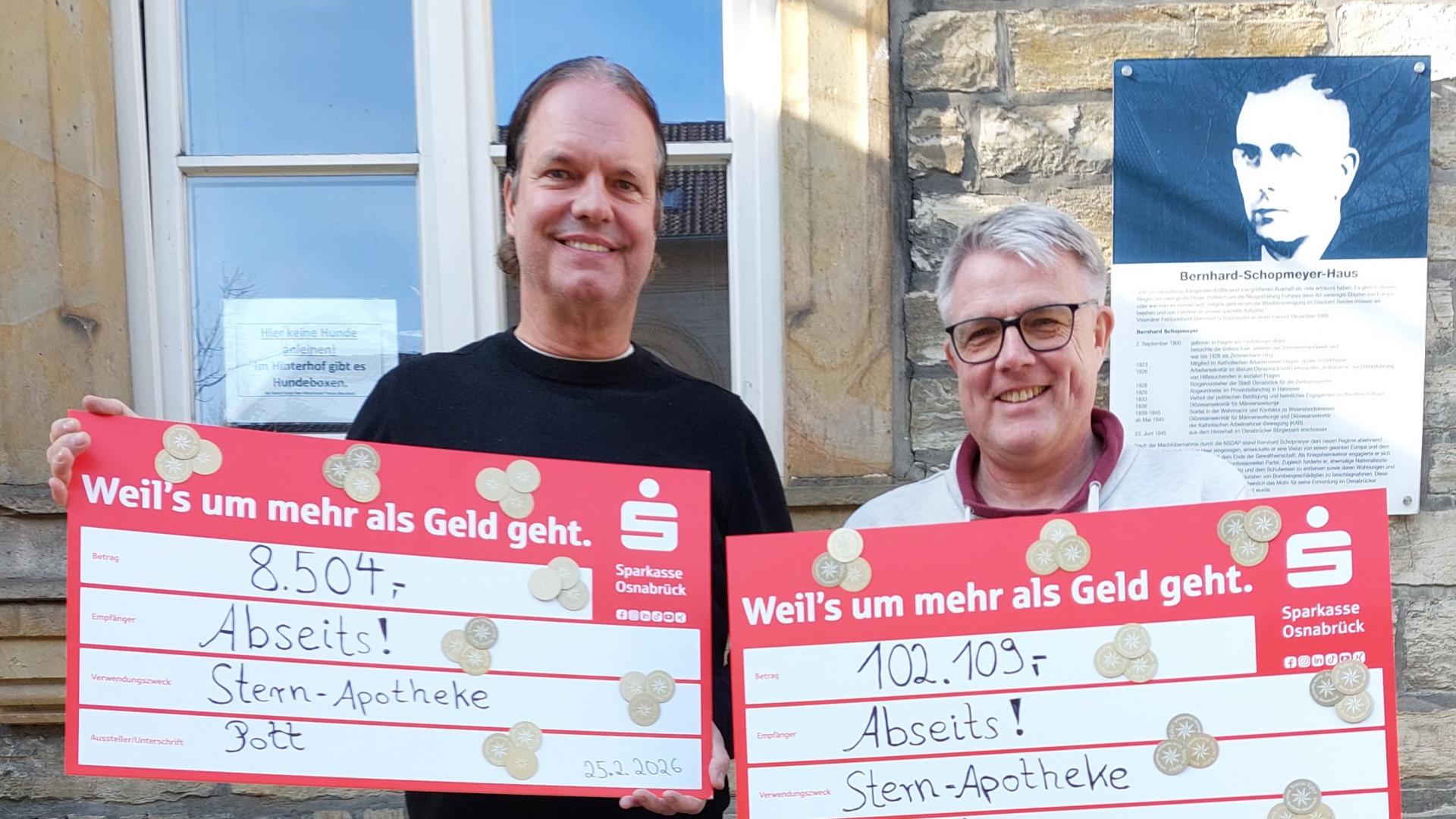 Zwei Männer halten einen übergroßen Scheck über 100 Tsd. Euro