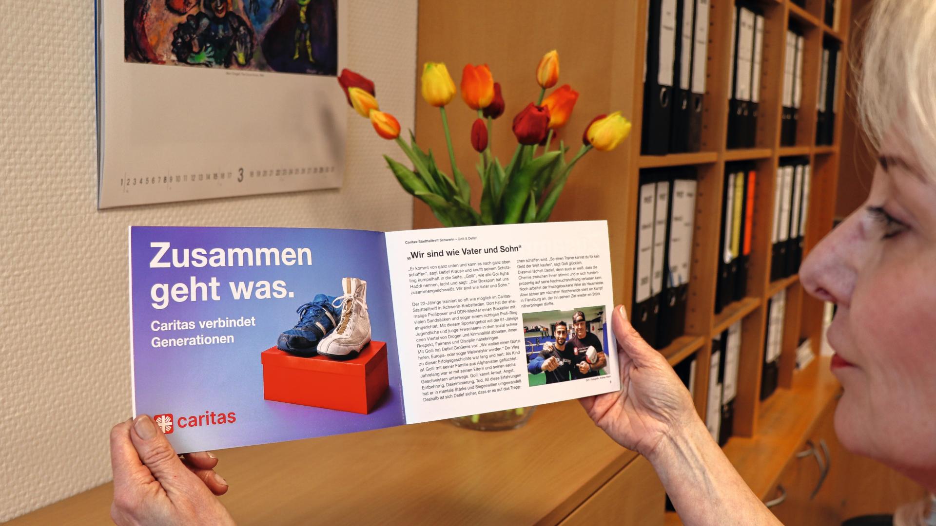 Eine Frau hält einen Flyer der Caritas